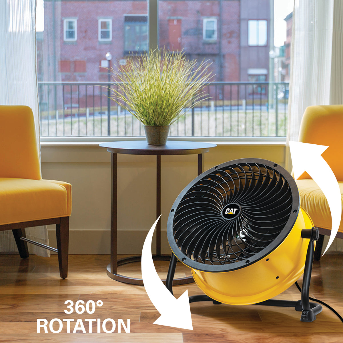 Yellow CAT floor fan shown in a living room setting with two orange chairs, a side table, and a window view. White arrows and text indicate 360° rotation.