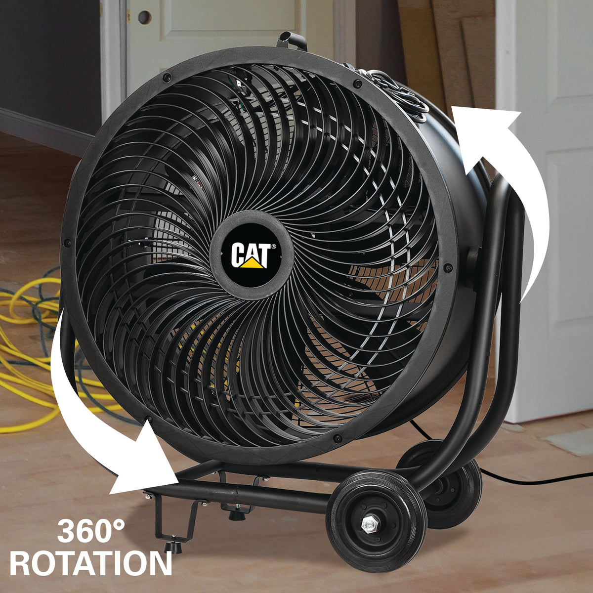 A black CAT industrial fan with a 360-degree rotation feature, shown in a home environment with white arrows indicating rotation and a yellow cable on the floor.