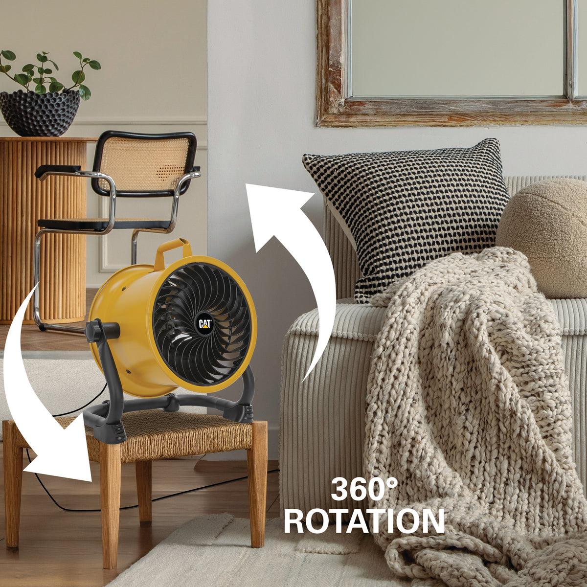 A yellow CAT floor fan shown in a living room setting, mounted on a wooden stool. White arrows illustrate the fan's 360-degree rotation capability, with the text '360° ROTATION' overlaid on the scene.